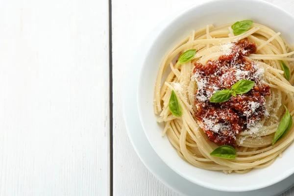 Spaghetti Bolognese dengan keju parmesan dalam mangkuk putih, pada latar belakang kayu warna — Stok Foto