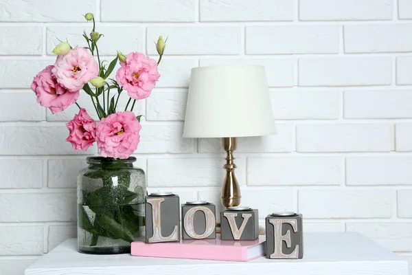 Beautiful flowers with table lamp on brick wall background — Stock Photo, Image