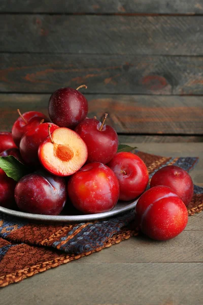 Ripe plums in metal plate on wooden background — Stock Photo, Image