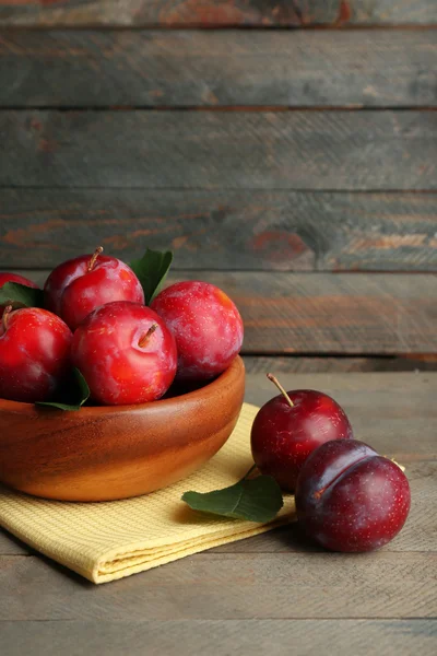 Ripe plums in bowl on wooden background — Stock Photo, Image