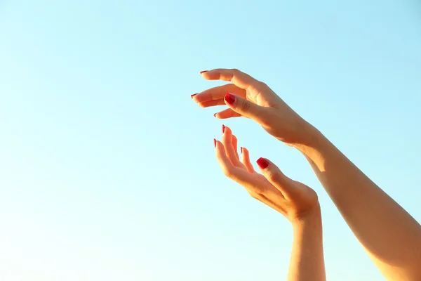 Manos femeninas sobre fondo azul cielo — Foto de Stock