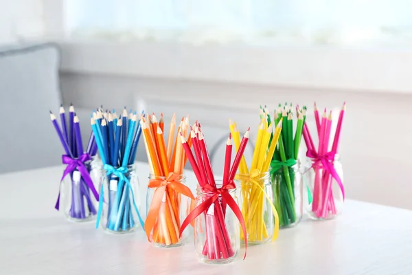 Lápis brilhantes em frascos de vidro na mesa — Fotografia de Stock