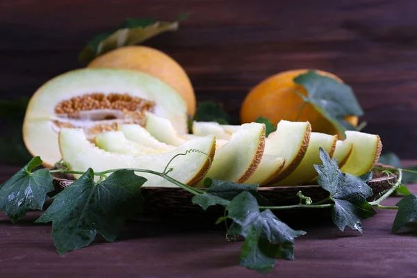 Melones maduros con hojas verdes sobre mesa de madera de cerca —  Fotos de Stock