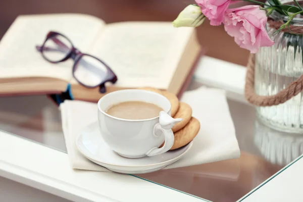 Šálek kávy s knihou na stole v obýváku — Stock fotografie
