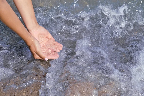 Dames hand aanraken van het blauwe water. — Stockfoto