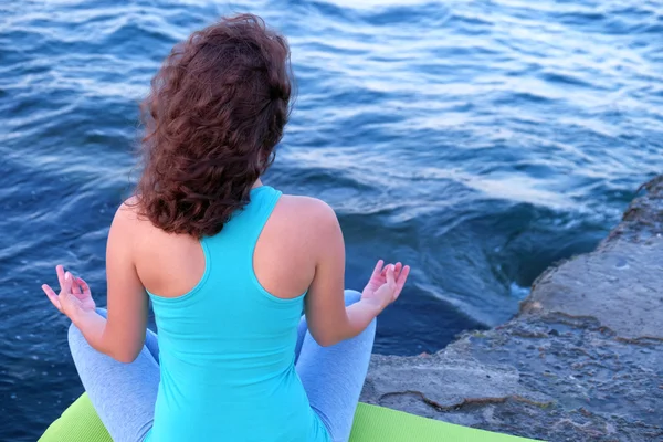 Молодая женщина практикует йогу на берегу моря — стоковое фото