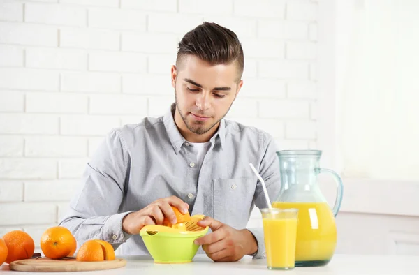 Ung man med citrus-frukt squeezer, förbereda apelsinjuice — Stockfoto