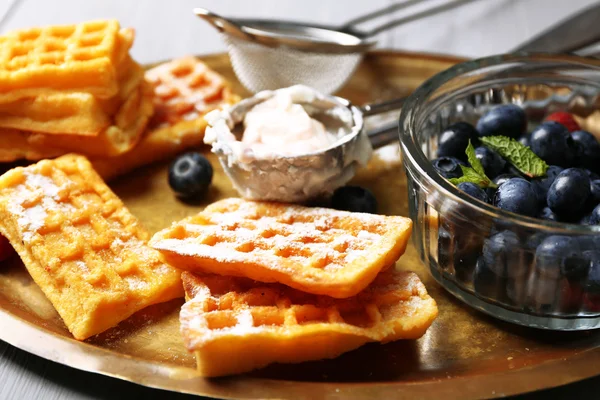 Süße hausgemachte Waffeln und Blaubeeren auf Tablett, auf farbigem Holzhintergrund — Stockfoto