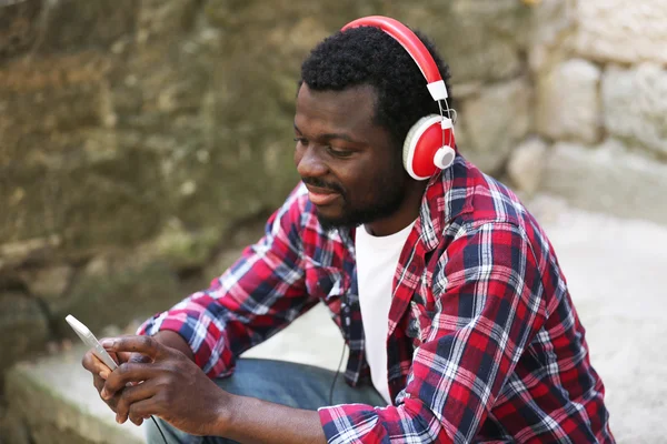 African American man listening music with headphones outdoors — Stock Photo, Image