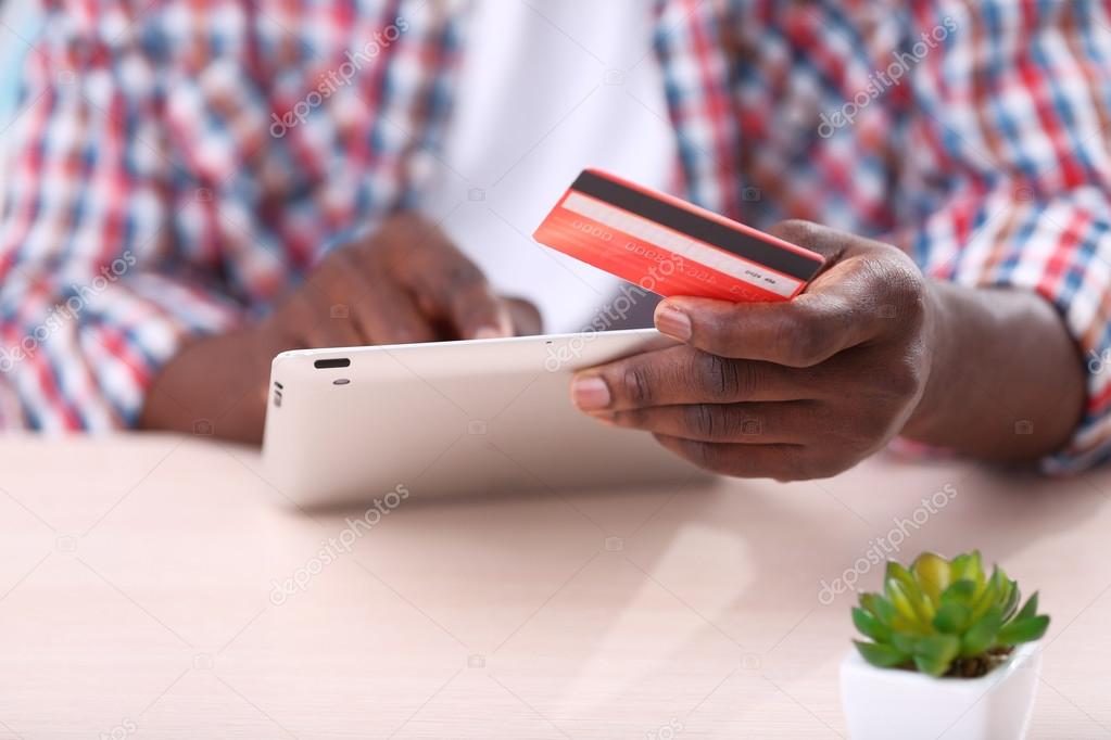 African American male hands with tablet and credit card at workplace