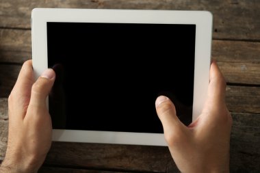 Ahşap masa arka plan üzerinde dijital tablet holding eller