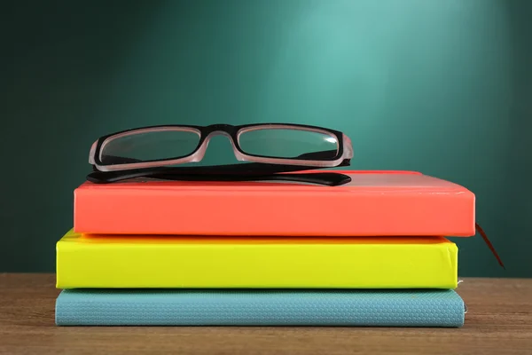 Stapel boeken met een bril op Bureau op groene schoolbord achtergrond — Stockfoto