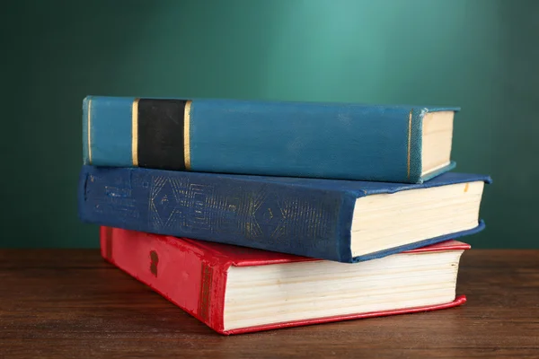 Stapel boeken op Bureau op groene schoolbord achtergrond — Stockfoto