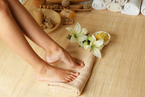 Женские ноги на мягком полотенце на фоне бамбукового коврика — стоковое фото