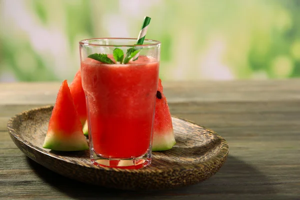 Glas av vattenmelon juice på träbord på suddig bakgrund — Stockfoto