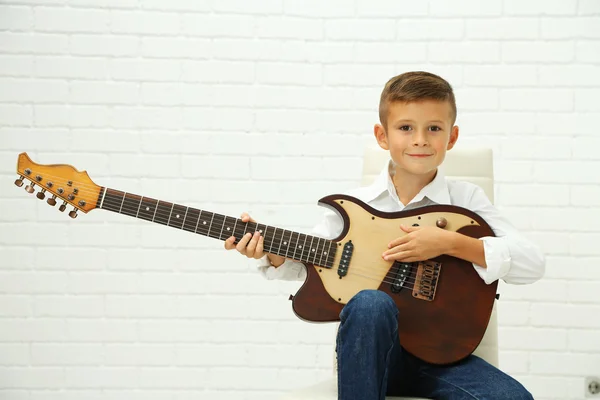 Malý chlapec, hrál na kytaru na světlé pozadí — Stock fotografie