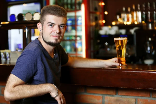 Junger Mann trinkt Bier in Bar — Stockfoto