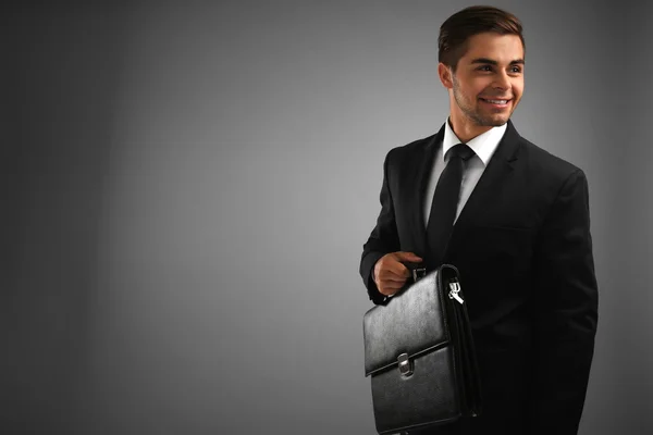 Elegant man in suit with briefcase on gray background — Stock Photo, Image