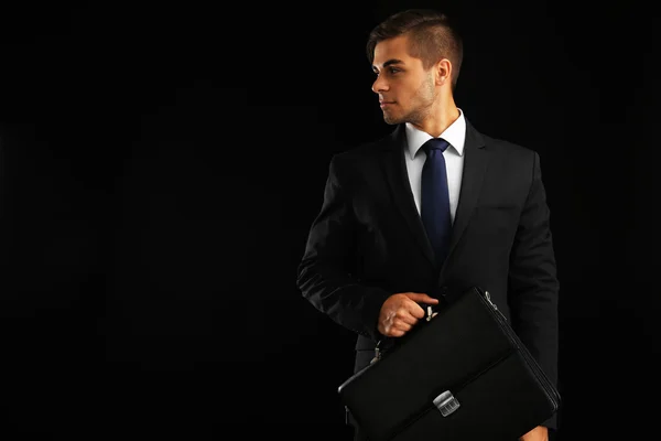 Elegant man in suit with briefcase on dark background — Stock Photo, Image