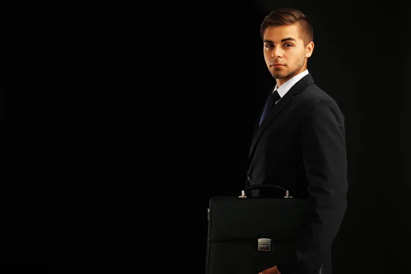 Elegant man in suit with briefcase on dark background — Stock Photo, Image