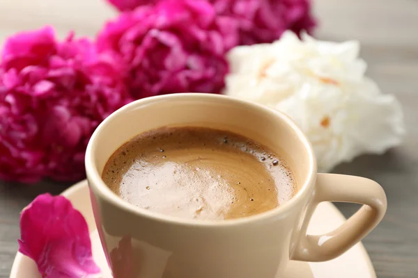 Composizione con tazza di caffè e fiori di peonia su fondo di legno — Foto Stock