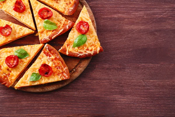 Fatias de pizza de queijo saboroso com manjericão e tomates cereja na mesa de perto — Fotografia de Stock