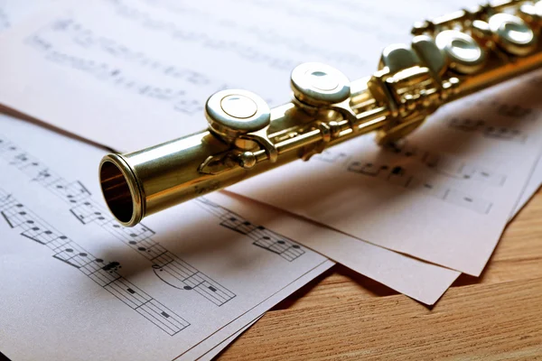 Zilveren fluit met muziek notities houten tafel close-up — Stockfoto