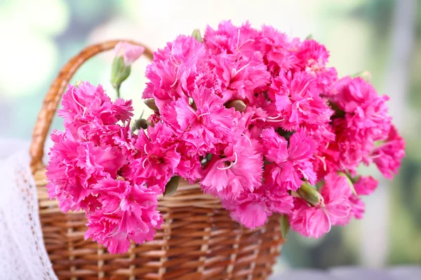 Beautiful bouquet of pink carnation in basket on bright background — Stock Photo, Image
