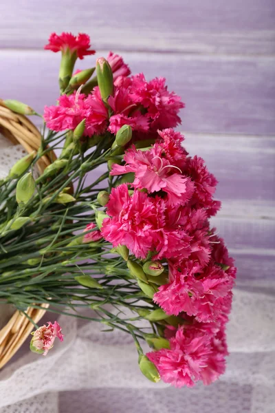 Vacker bukett rosa nejlika i korg på träbord nära håll — Stockfoto