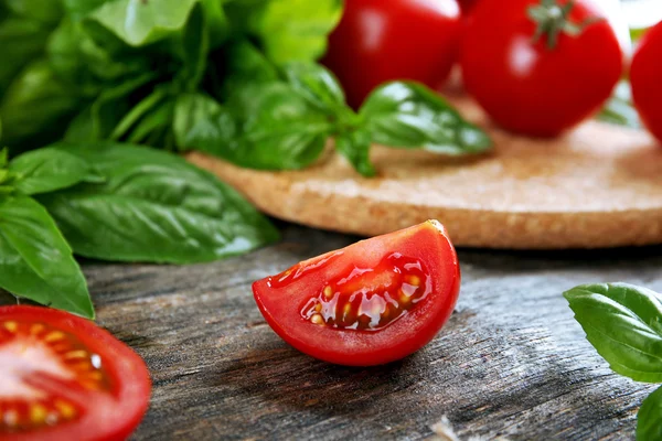 Tomates cherry con albahaca sobre mesa de madera de cerca — Foto de Stock