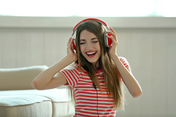 Mulher ouvindo música em fones de ouvido no quarto — Fotografia de Stock