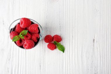 Taze Kırmızı Ahududu ahşap arka plan üzerinde metal kovada