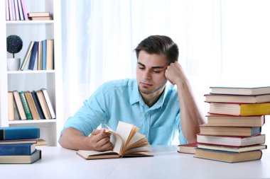 Genç adam odada masasında kitap okumak