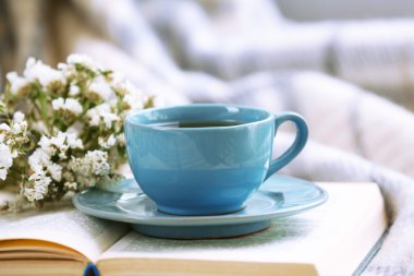 Mavi fincan kahve ile Divan odasında açık kitap