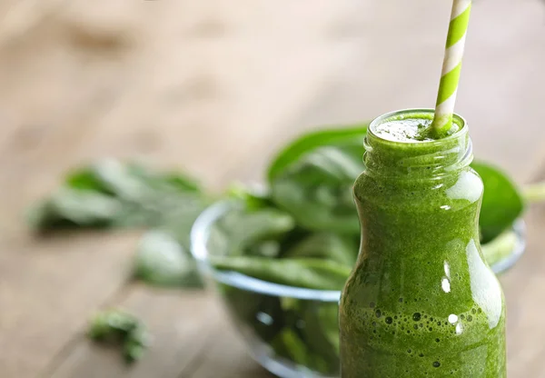 Bouteille en verre de jus d'épinards sur table en bois, gros plan — Photo