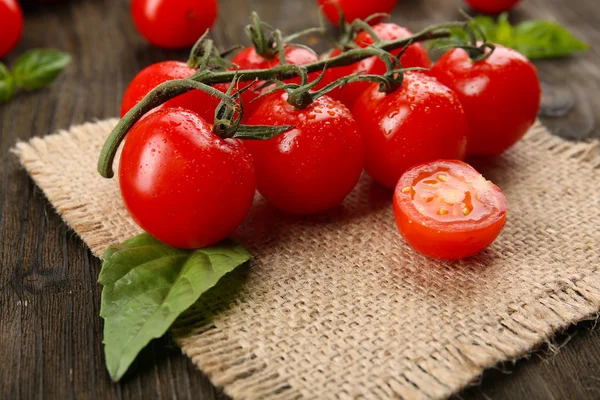 Fresh tomatoes with basil on wooden table close up — Stock Photo, Image