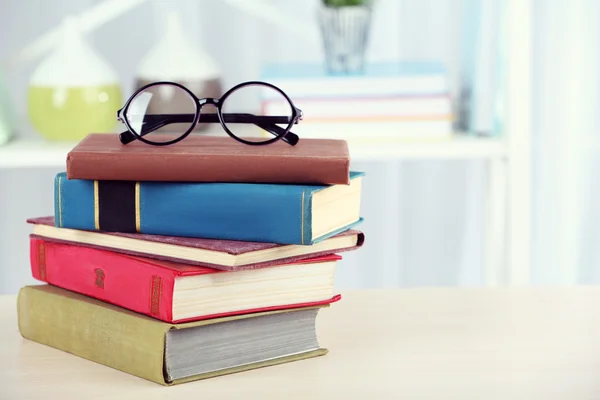 Pila di libri con occhiali su tavolo di legno in camera — Foto Stock