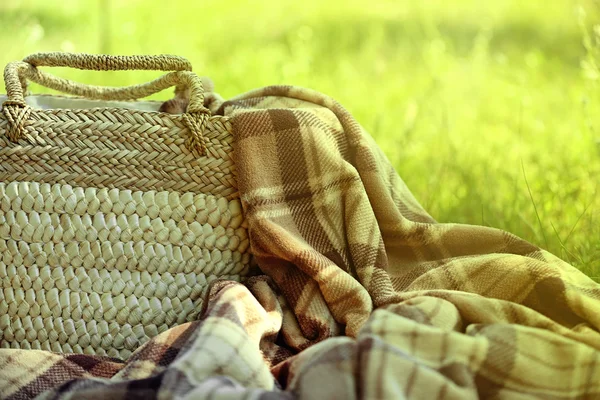 Flätad korg och pläd för picknick på grönt gräs — Stockfoto