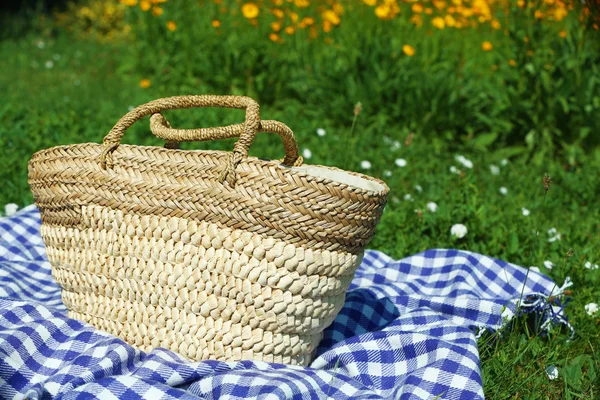 Rieten mand en Plaid voor picknick op groen gras — Stockfoto