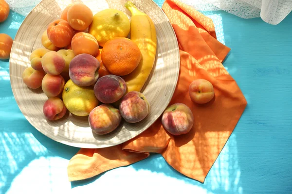 Куча свежих фруктов на подносе на деревянном столе — стоковое фото