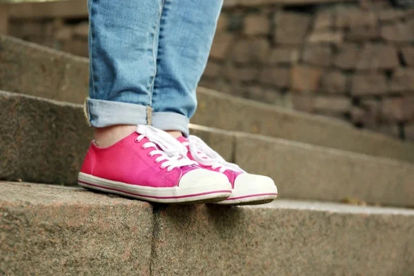 Pies femeninos en zapatos de goma rosa en escaleras de piedra — Foto de Stock