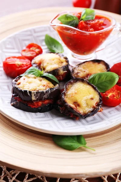 Dish of eggplant with cherry tomatoes and cheese in white plate on wooden table, closeup — Stock Photo, Image
