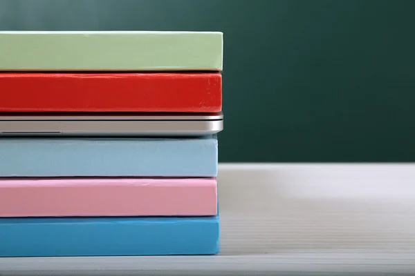 Bücherstapel mit Laptop auf dem Tisch im Klassenzimmer — Stockfoto