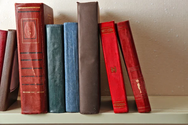Gamla böcker på hyllan, närbild, på ljus vägg bakgrund — Stockfoto