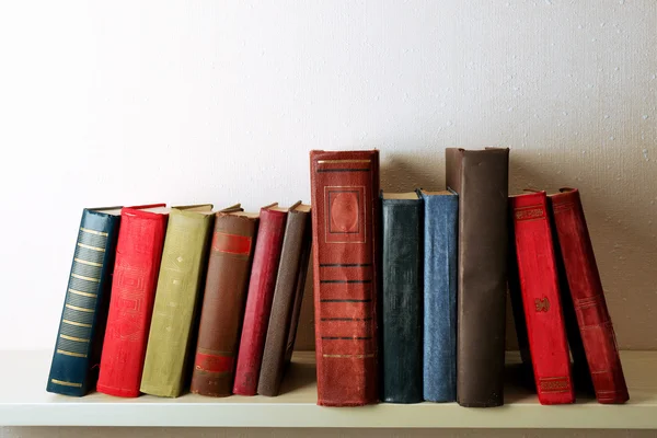 Livros antigos na prateleira, close-up, no fundo da parede de luz — Fotografia de Stock