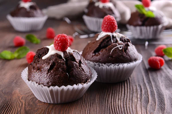 Leckere Schokoladen-Cupcakes mit Beeren und frischer Minze auf Holztisch aus nächster Nähe — Stockfoto