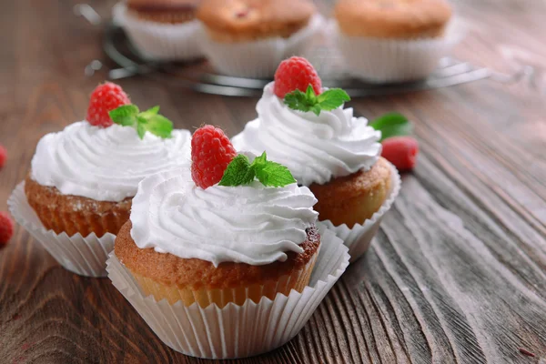 Deliciosos cupcakes com bagas e hortelã fresca na mesa de madeira fechar — Fotografia de Stock