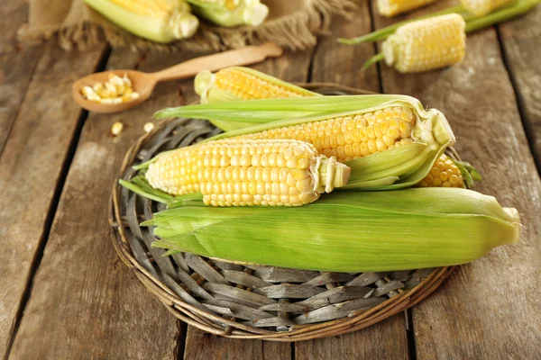 Frischer Mais auf Kolben auf Weidenmatte auf Holztisch, Nahaufnahme — Stockfoto