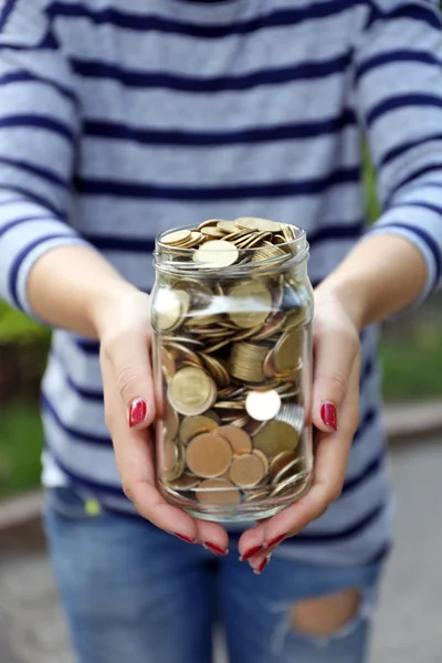Woman holding money jar with coins