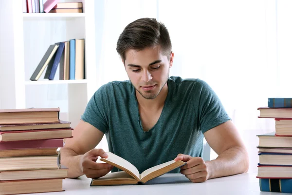 Jonge man leesboek aan tafel op kamer — Stockfoto